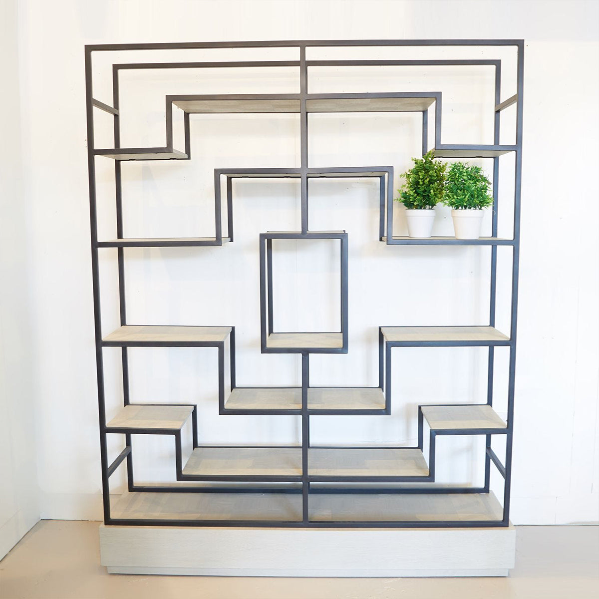 Geometric shelf with wooden shelves and metal frame against a white wall