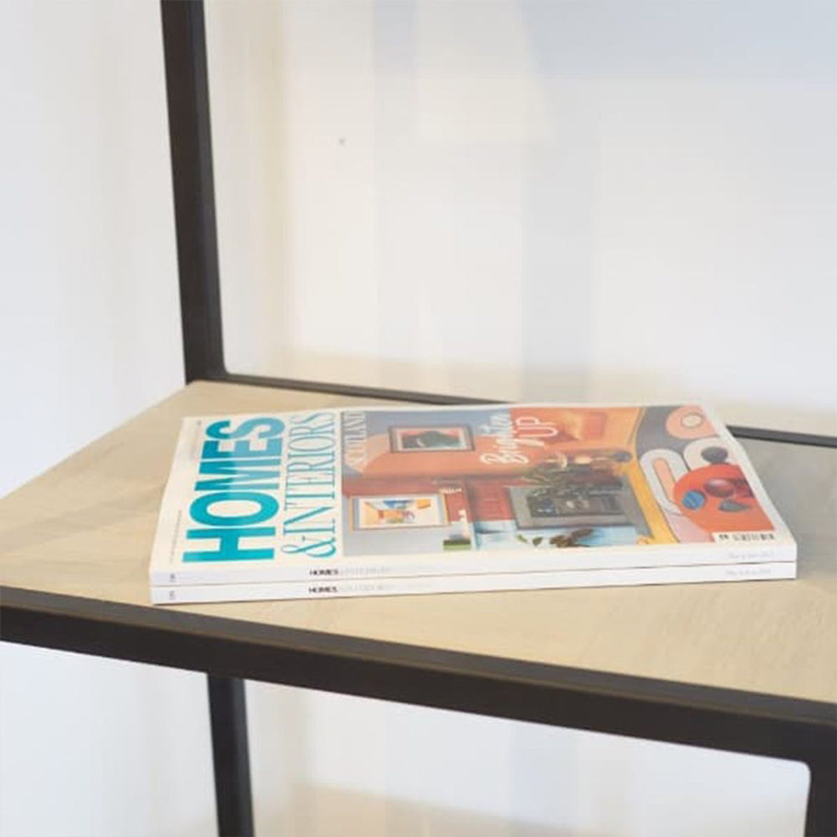 Stack of magazines on a white & black shelving unit with a blurred background