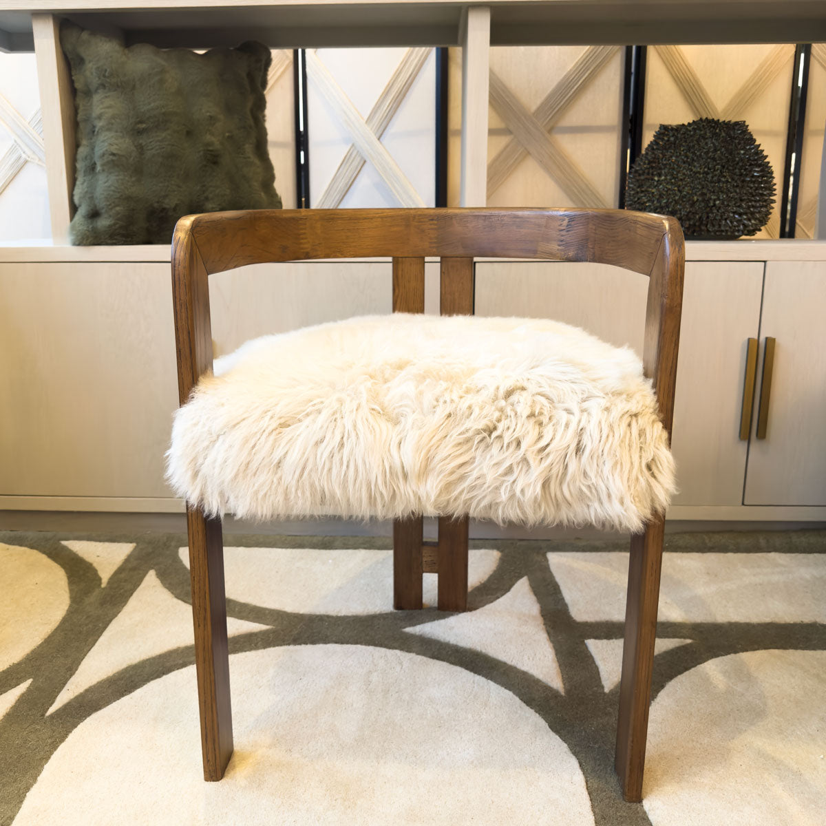 Wooden chair with a fluffy white cushion in a room setting.