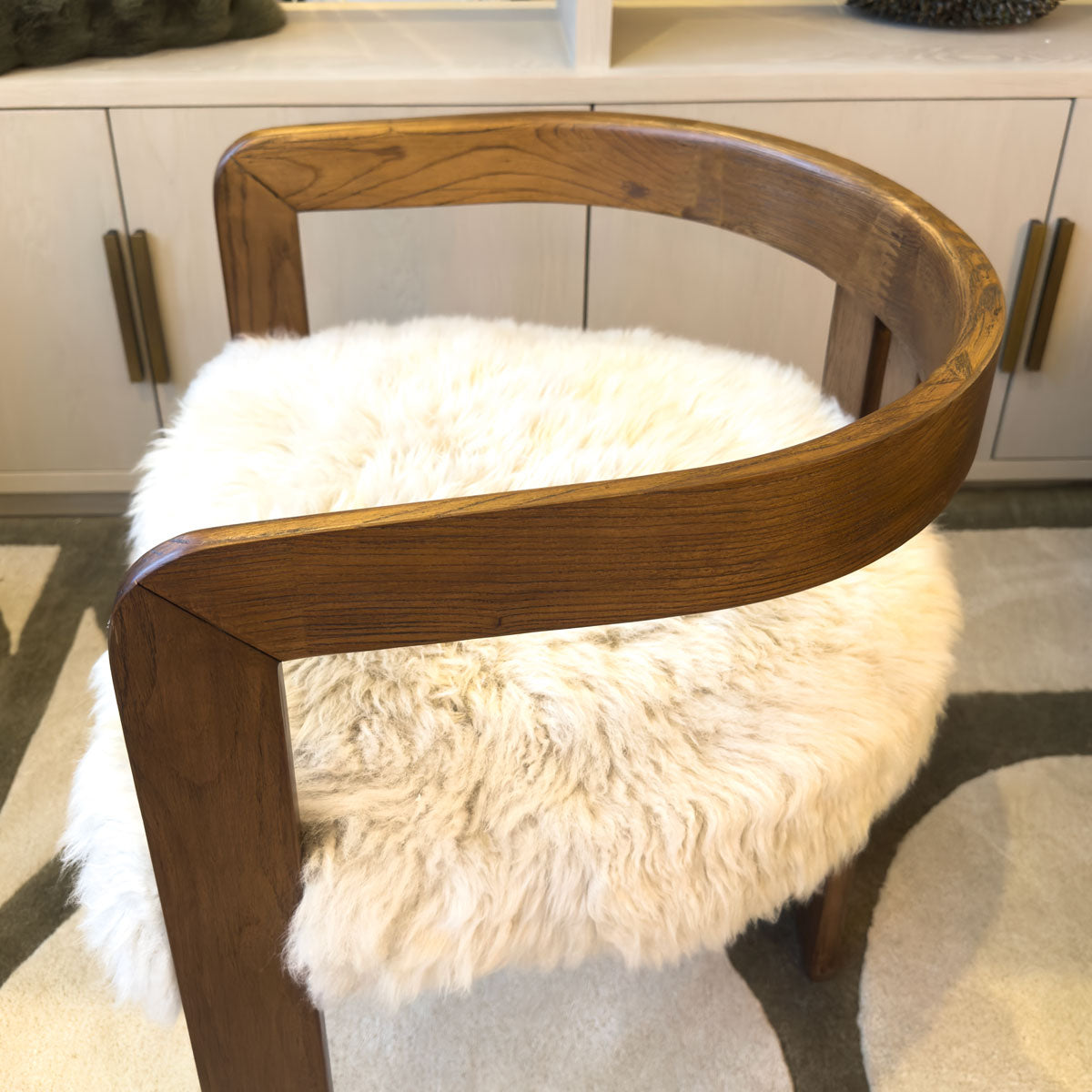 Wooden chair with a fluffy white cushion on a neutral background