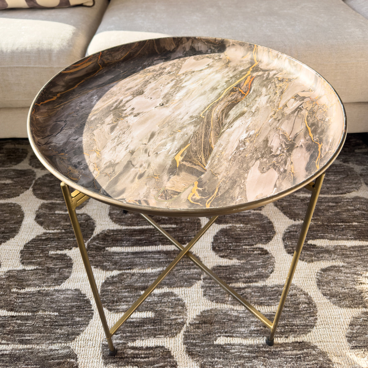 Round marble table with gold legs on a patterned rug