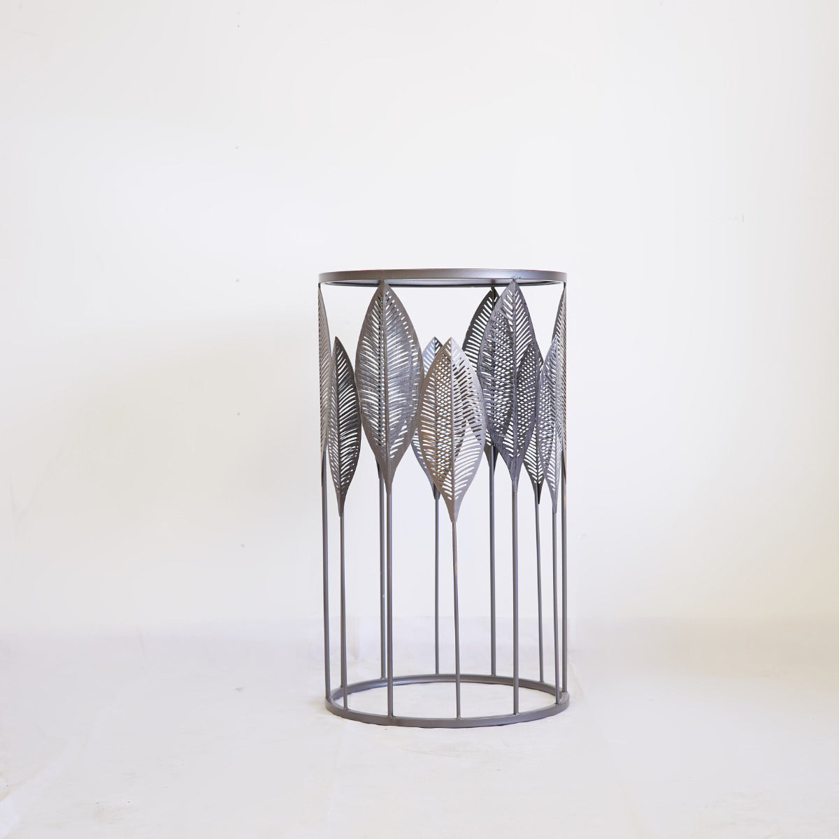 Decorative metal accent table with leaf pattern on a white background