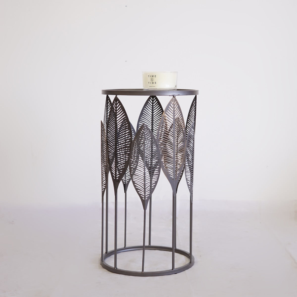 Decorative metal accemt table in silver with leaf pattern on a white background