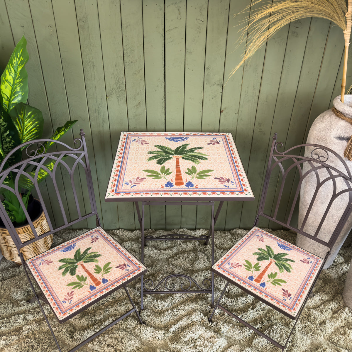 Patterned bistro set with decorative table and chairs featuring palm tree design on a textured floor.