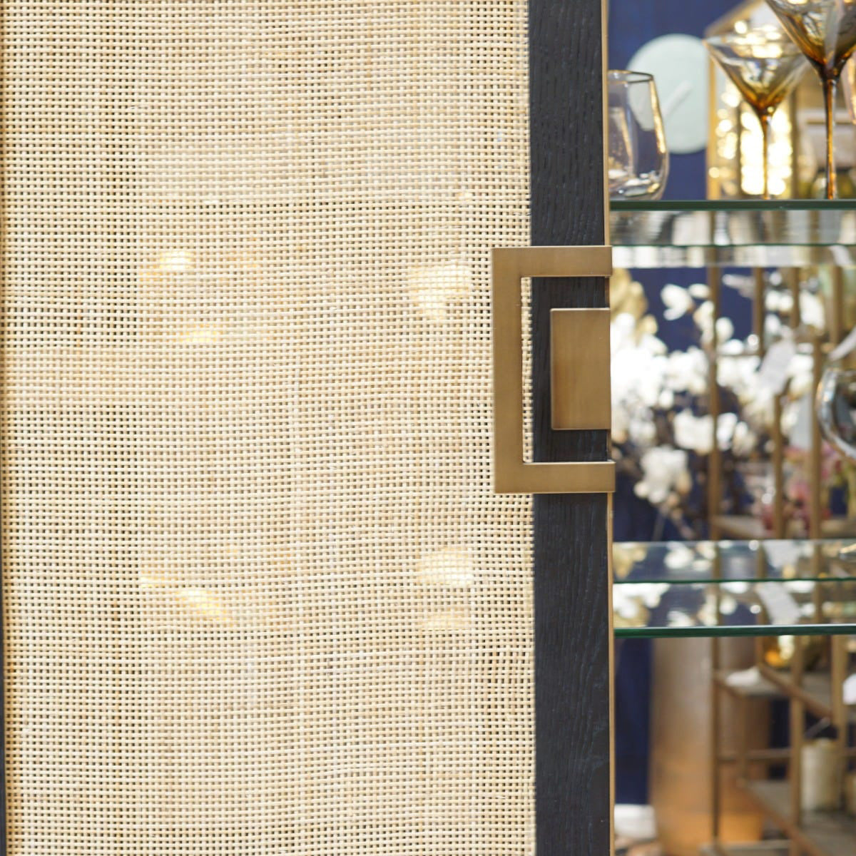 Decorative rattan bar cabinet with gold square handle in a room setting