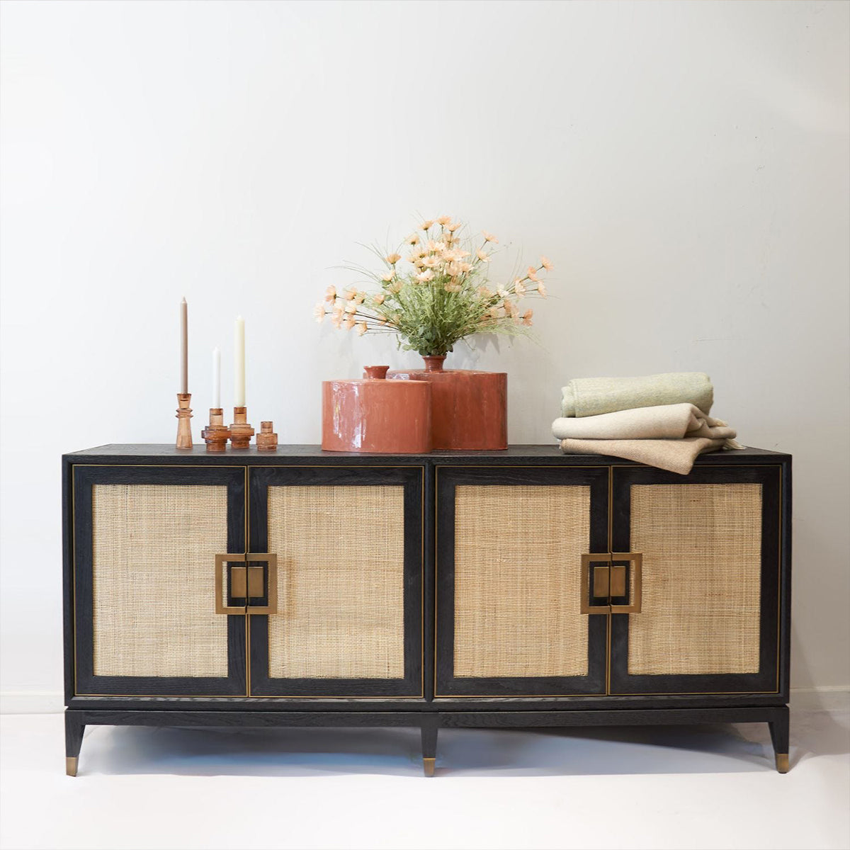 Decorative sideboard with rattan doors and coral vases and a white background
