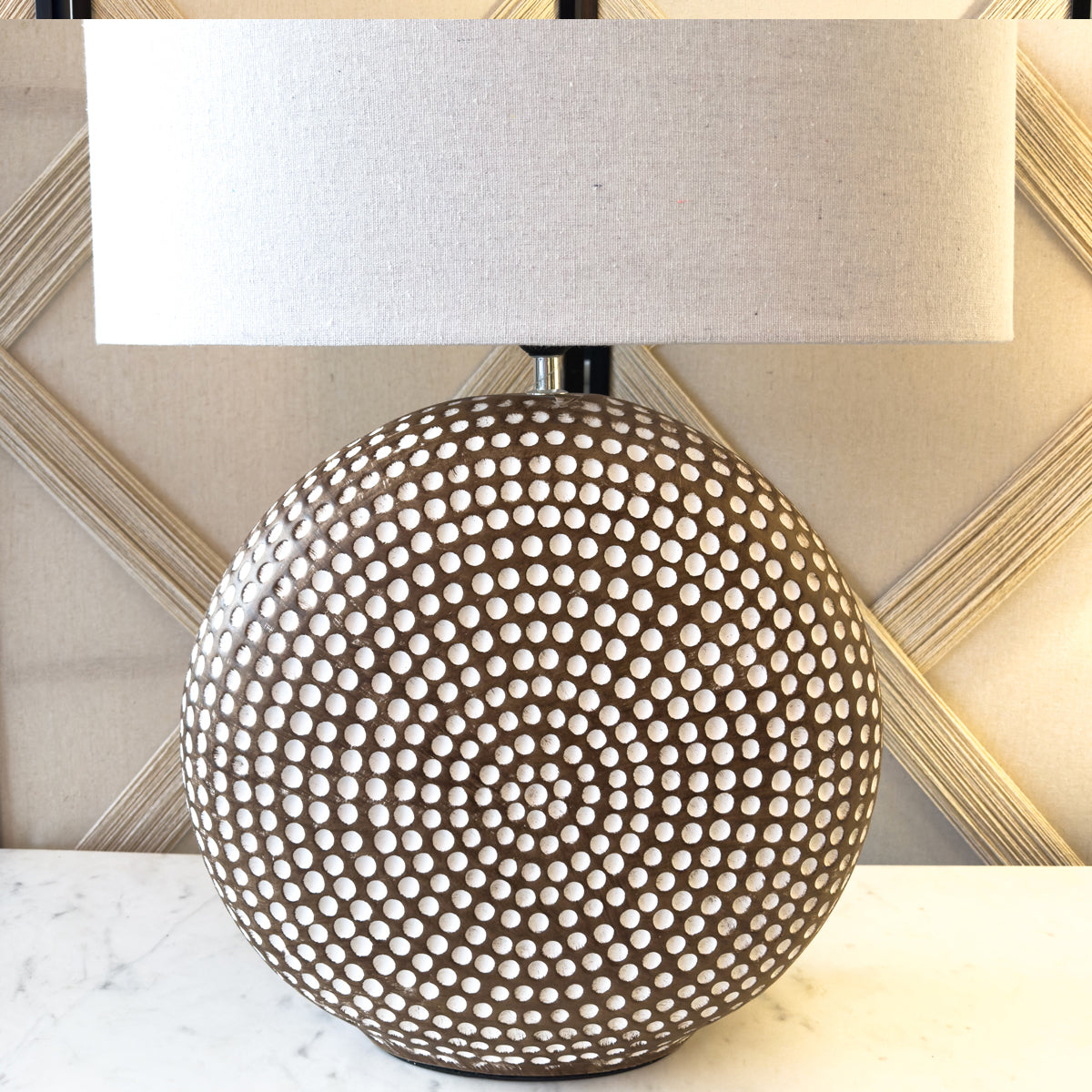 A circular brown table lamp with white dimples, and a complementary white shade.