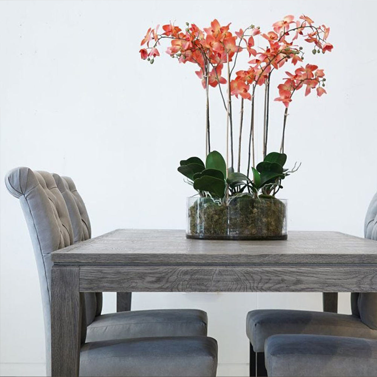Parquet greyed oak dining table with a pink orchid in glass dish on top