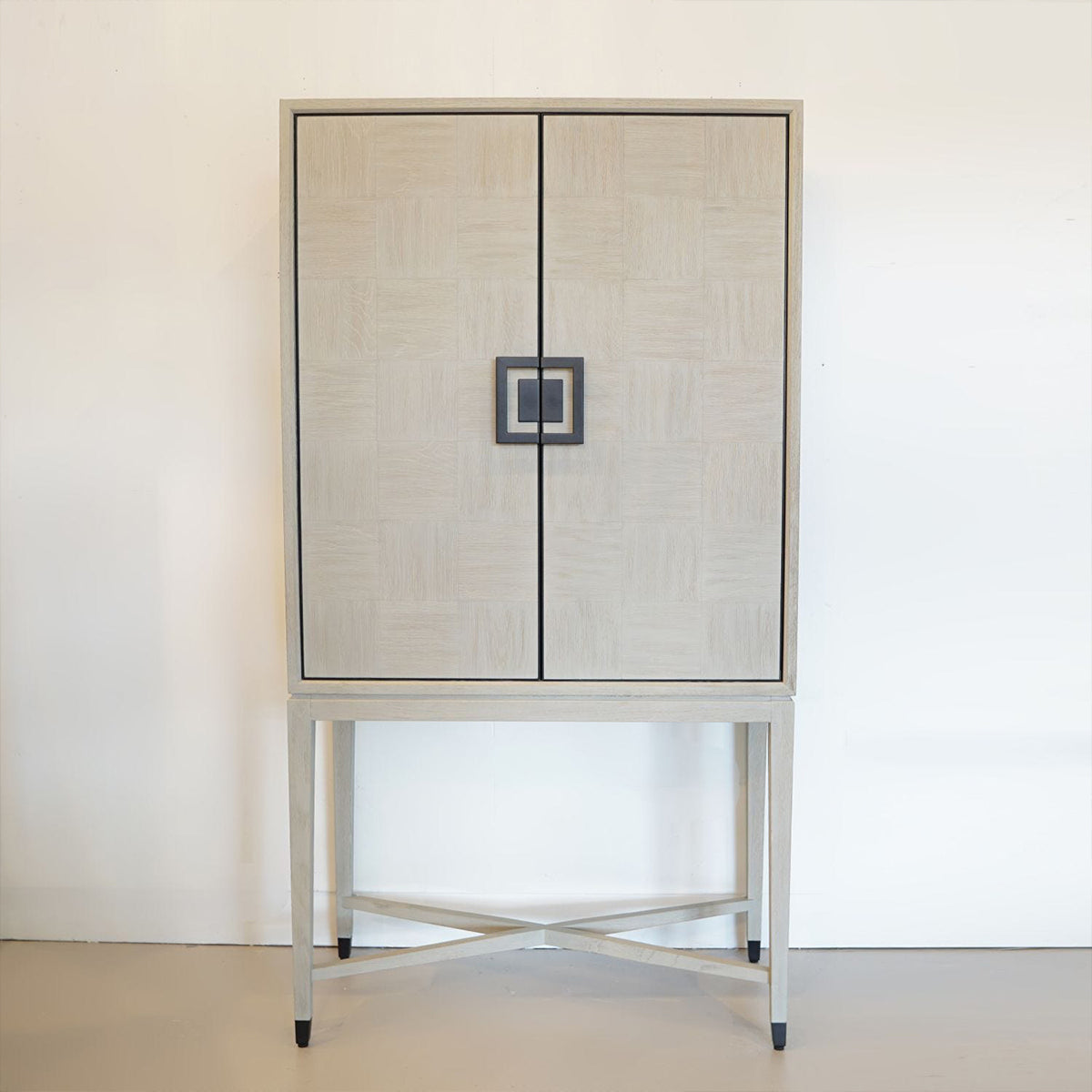 A white oak bar cabinet with black iron inlay, featuring a contemporary design with mirrored interior shelving.