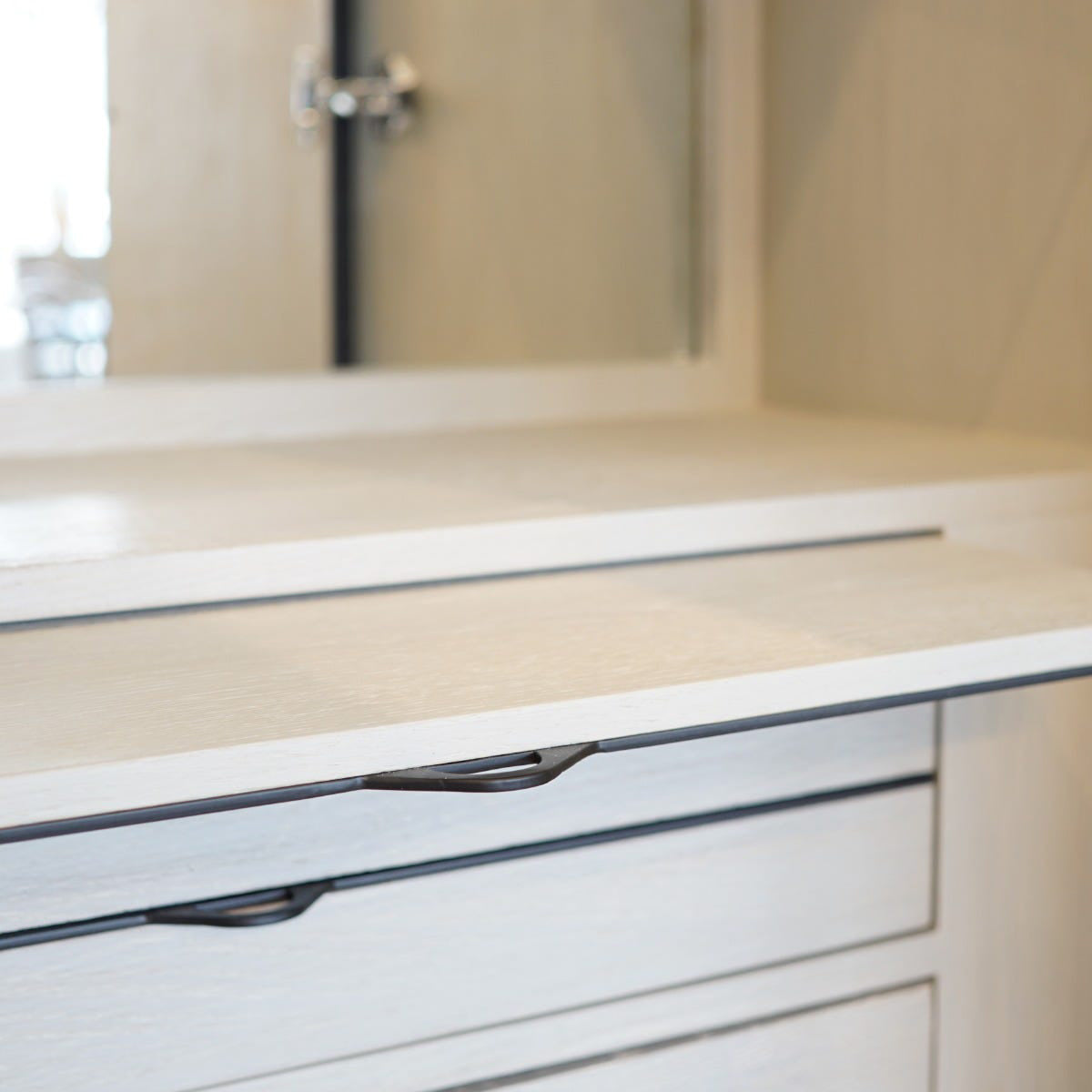 Close-up of a bar cabinet interior with a glass front and metallic handles.