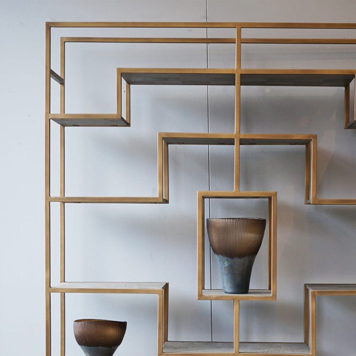 Decorative wall shelf with geometric design and two brown bowls on a white background