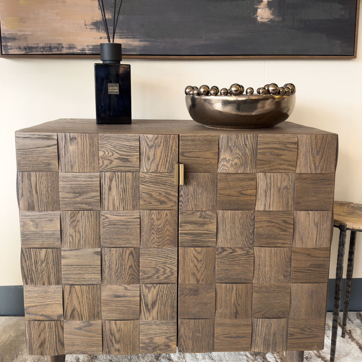 Wooden sideboard with parquet pattern, black vase, and decorative bowl in a room setting.