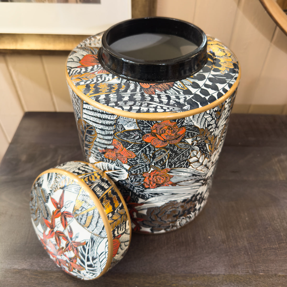 Decorative cylindrical container with floral pattern on a wooden surface