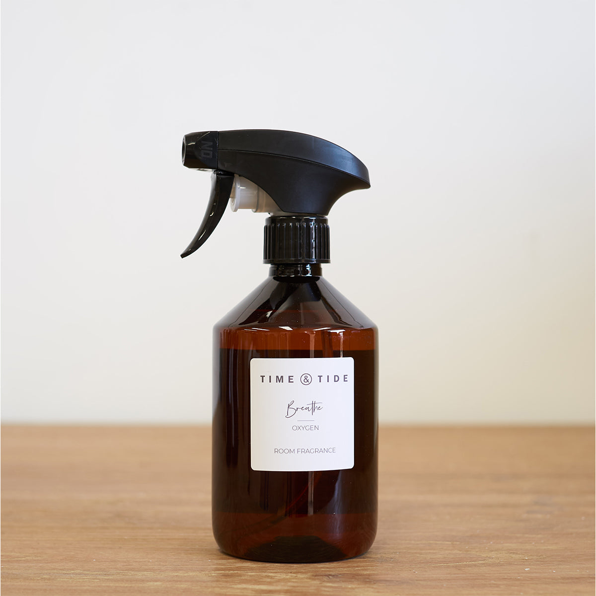 Brown fresh home spray bottle with black nozzle on a wooden surface and light background