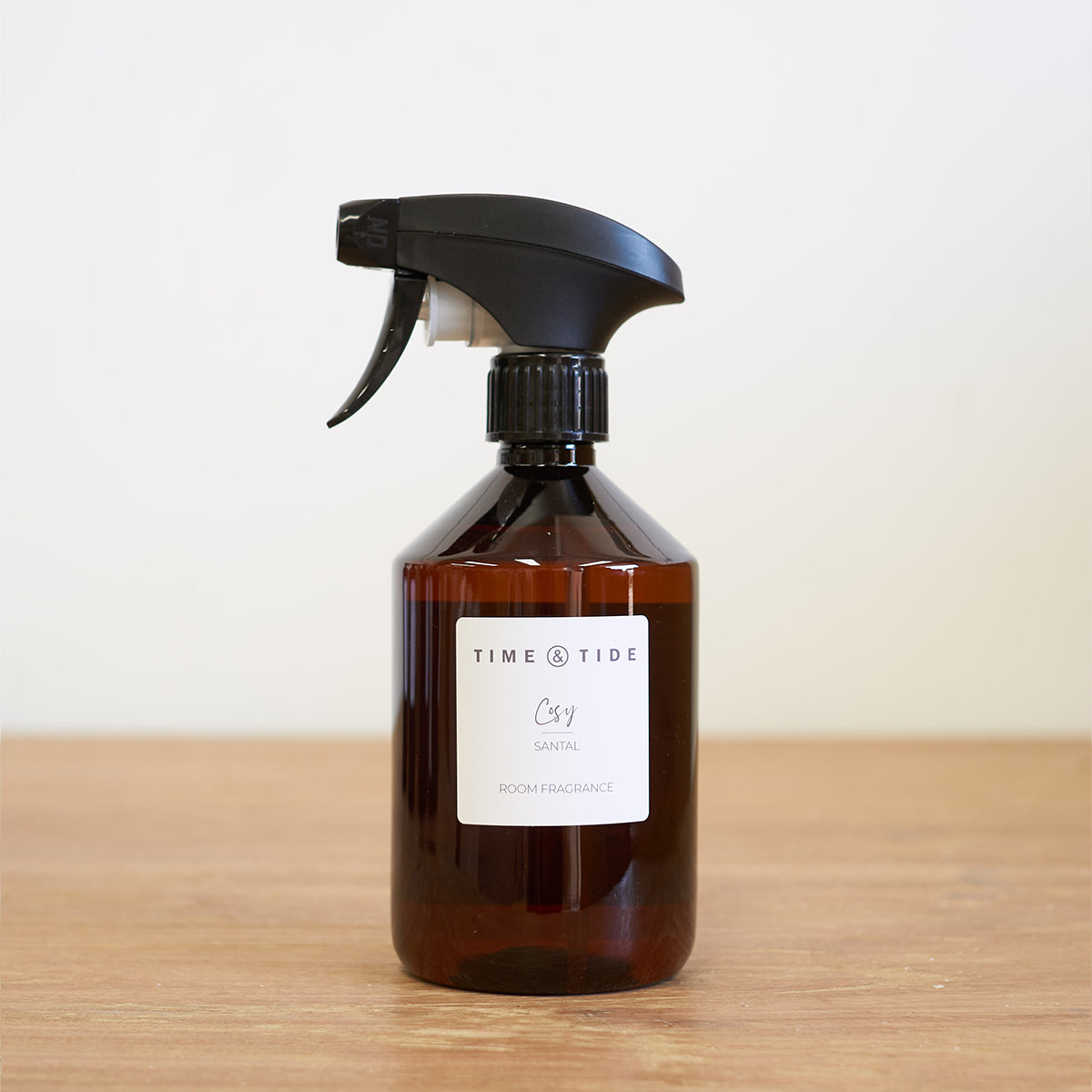 Brown spray bottle with black nozzle on a wooden surface and light background