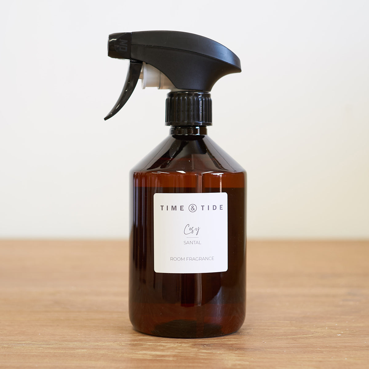 Brown room spray bottle with black nozzle on a wooden surface