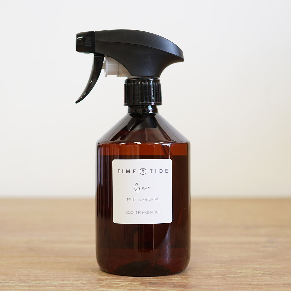 Herbal room spray bottle with black nozzle on a wooden surface
