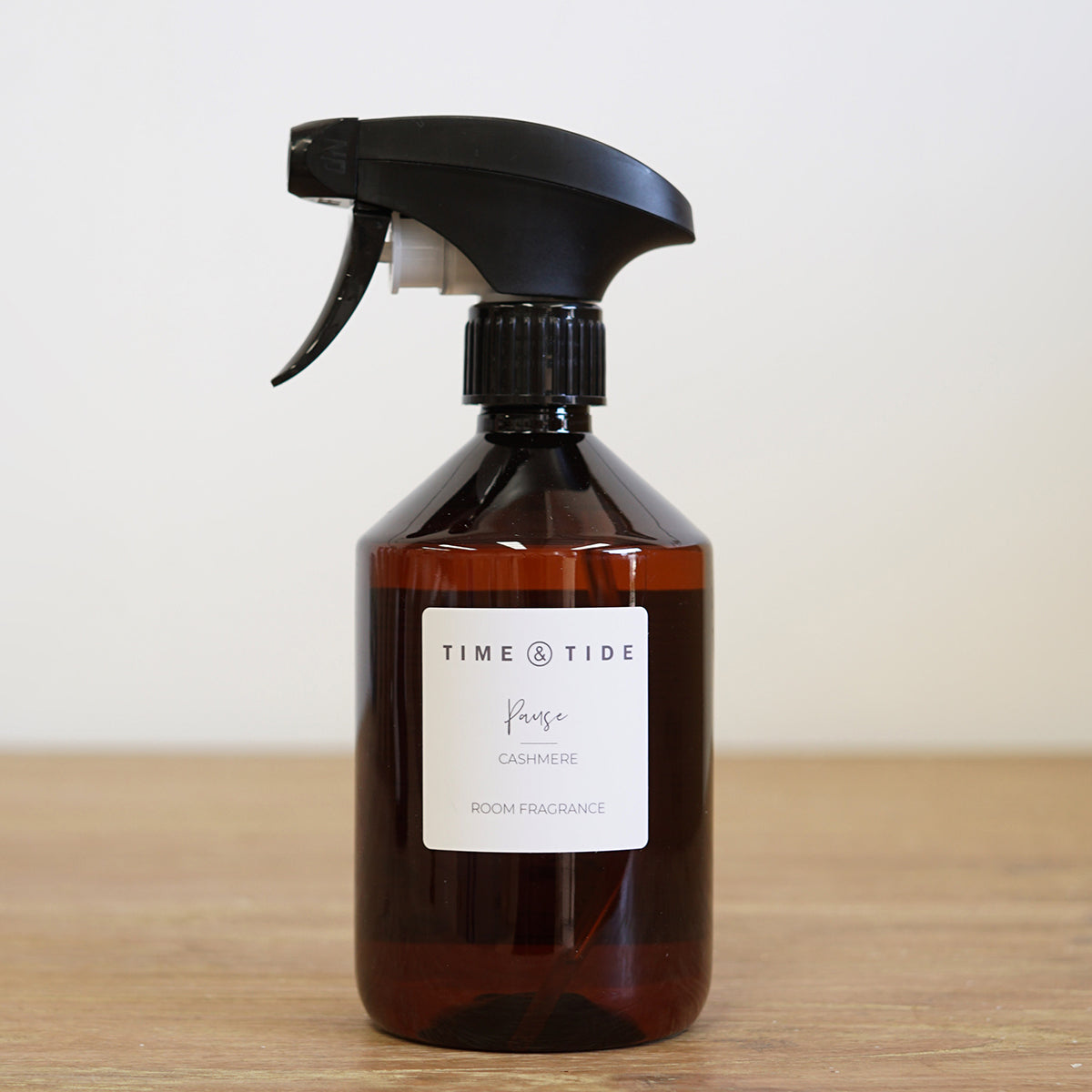 Floral room spray bottle with black nozzle on a wooden surface