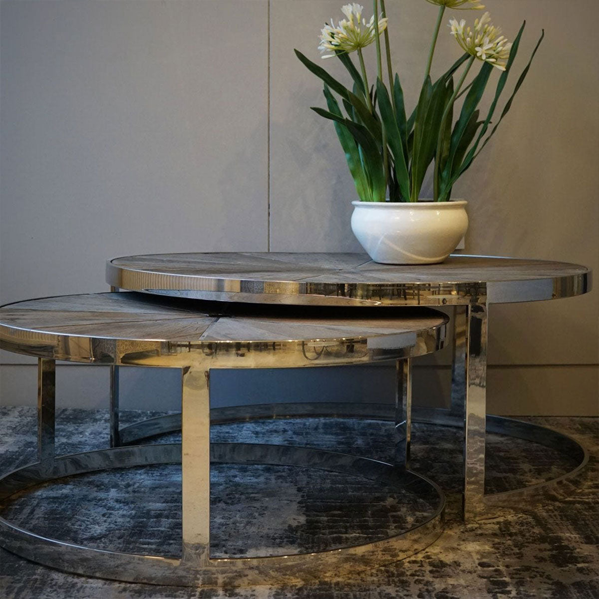 Set of 2 reclaimed wooden coffee tables with metal bases, and a vase of white flowers
