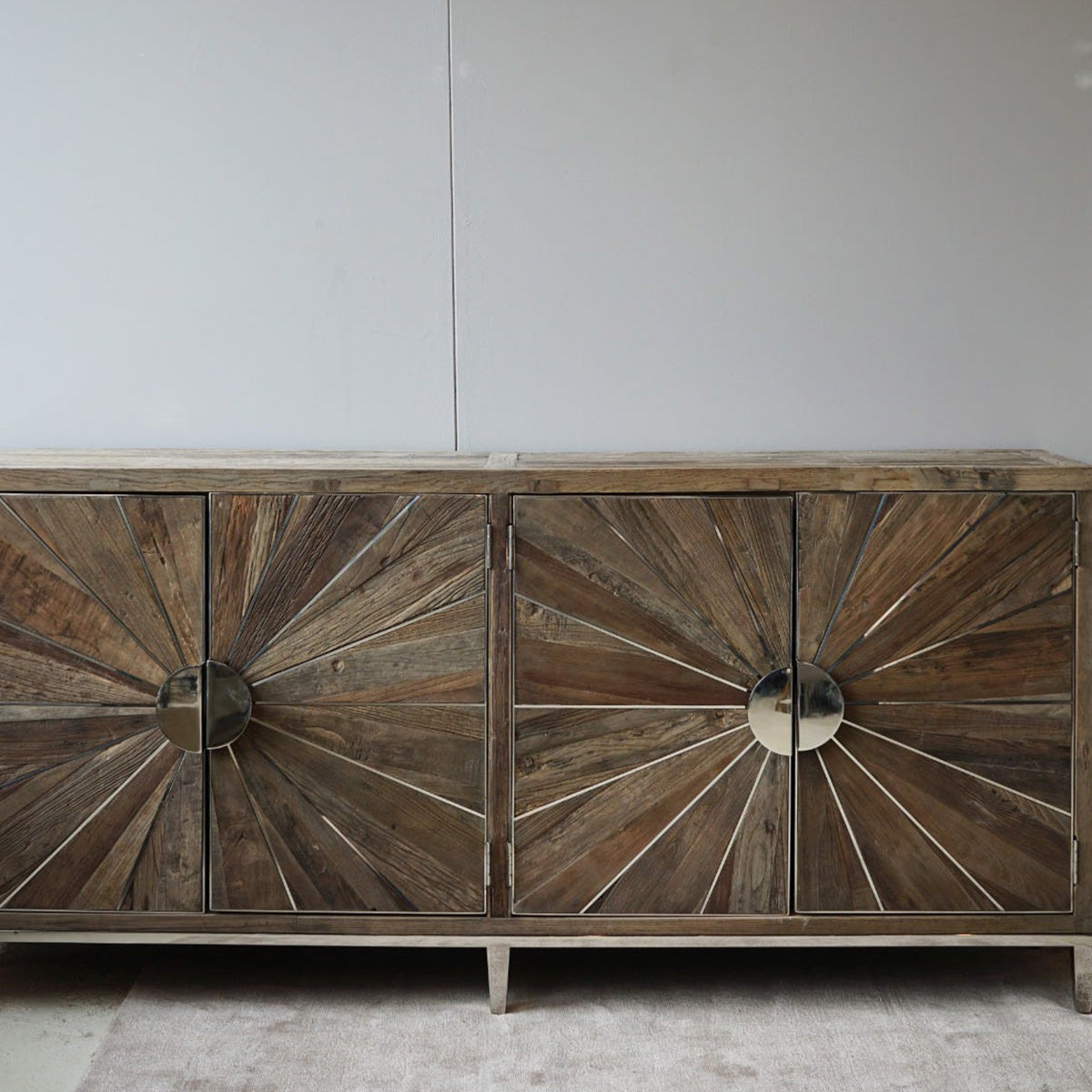 Wooden reclaimed wood cabinet with sunburst design on a white wall background