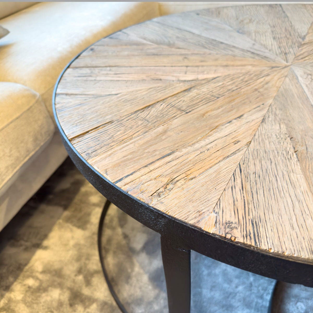 Round wooden table with a black metal base in an indoor setting