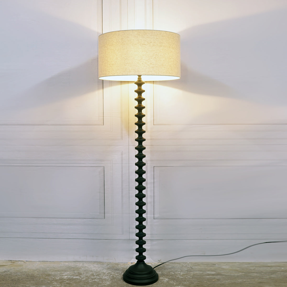 Floor lamp with a decorative base against a white wall