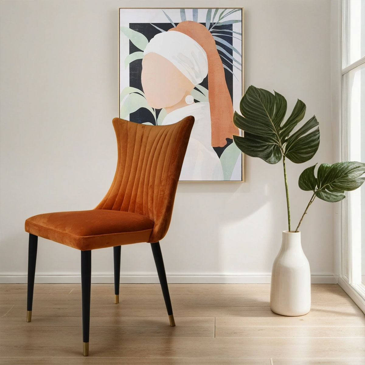 Orange chair in a room with a painting and plant