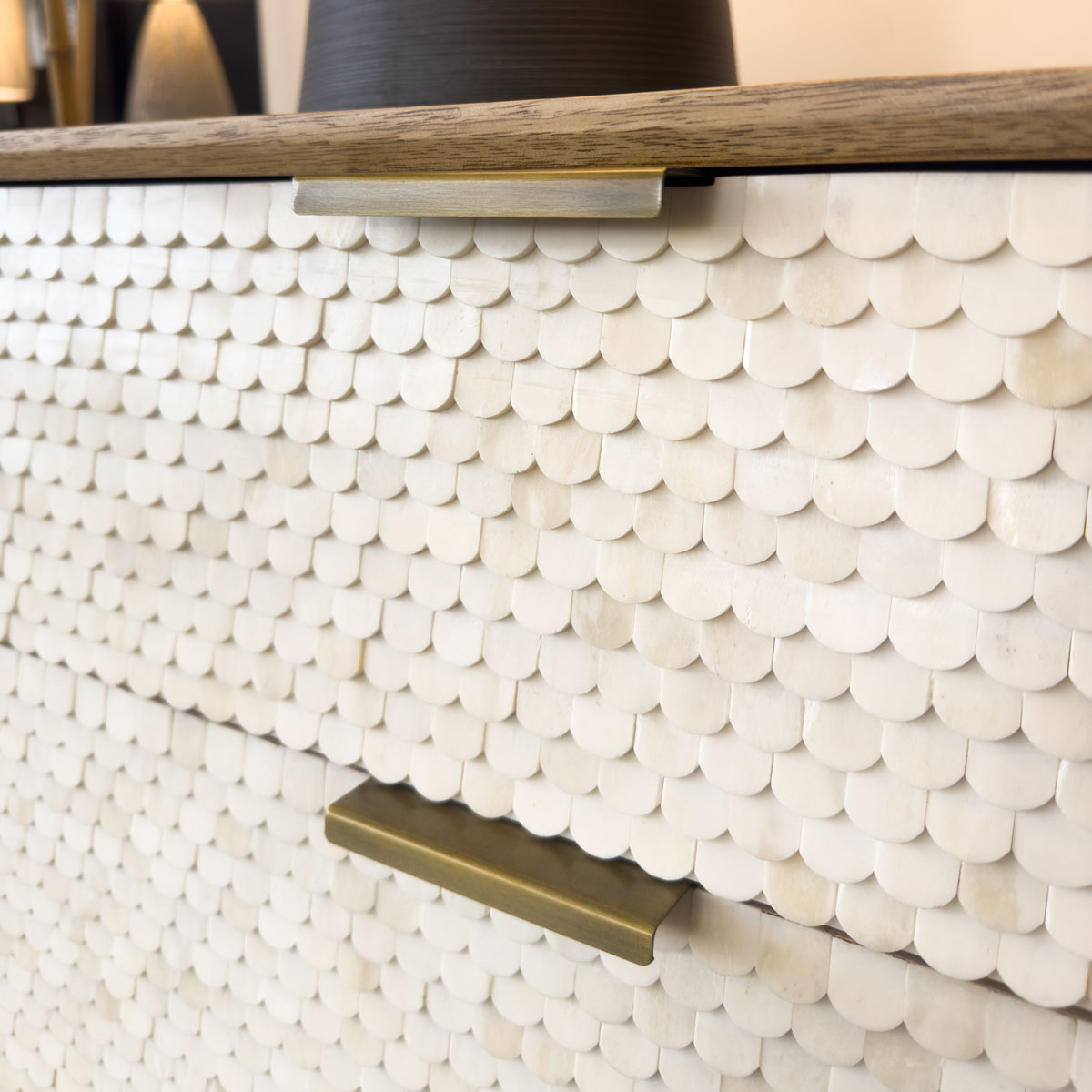Close-up of a decorative cabinet with shell-like pattern and brass handles.