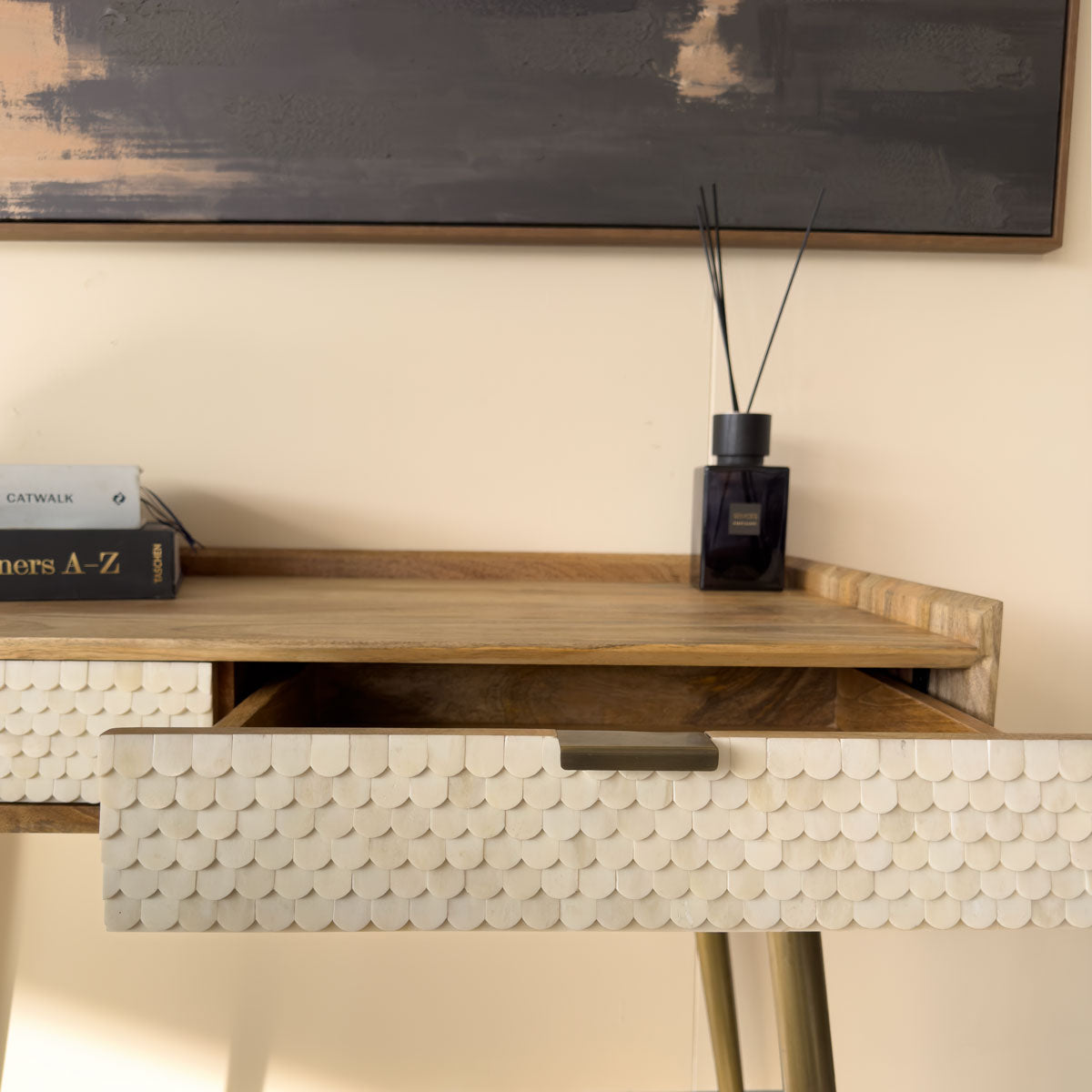 Wooden scalloped desk with decorative items against a neutral wall