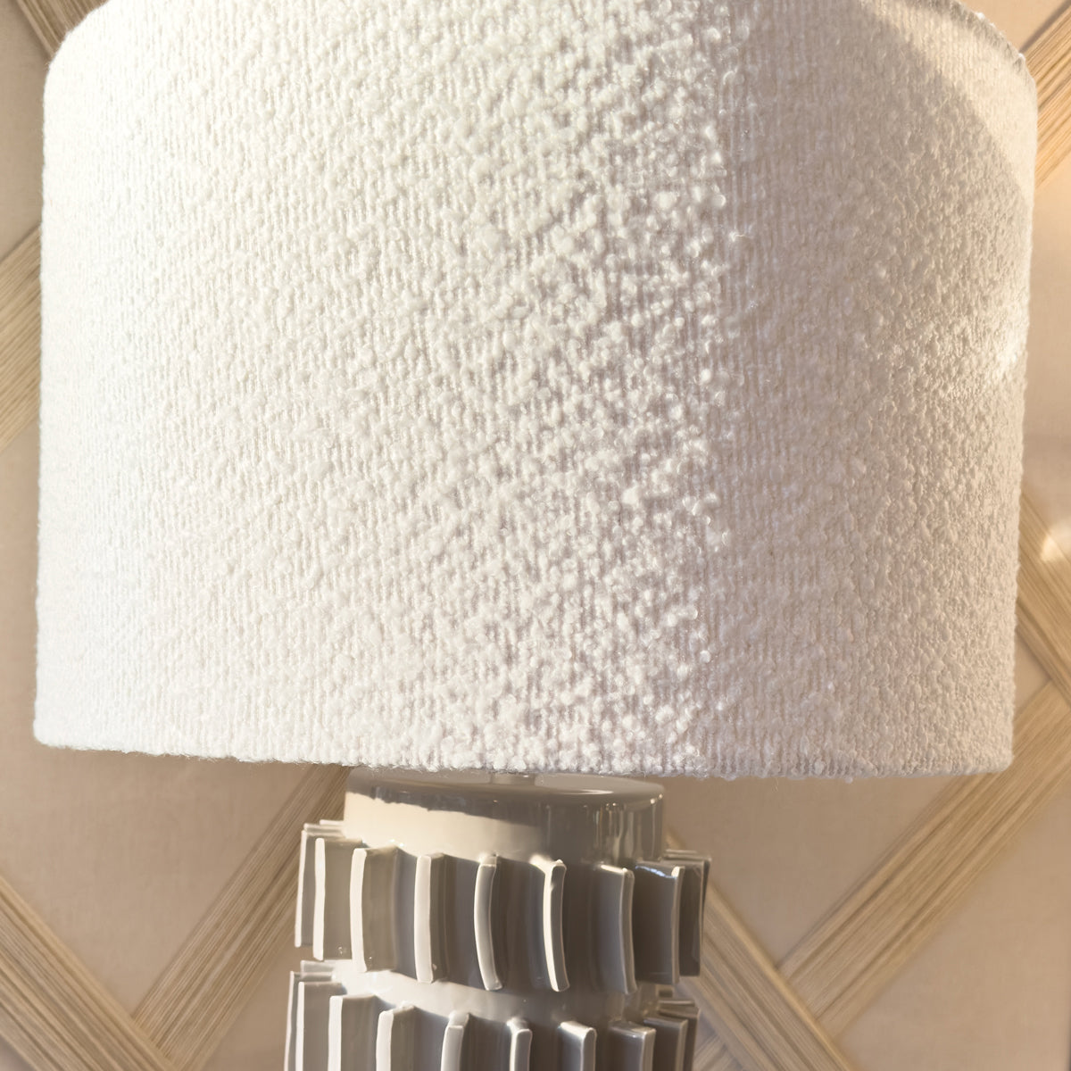 A grey tiled table lamp with a textured white boucle lamp shade.