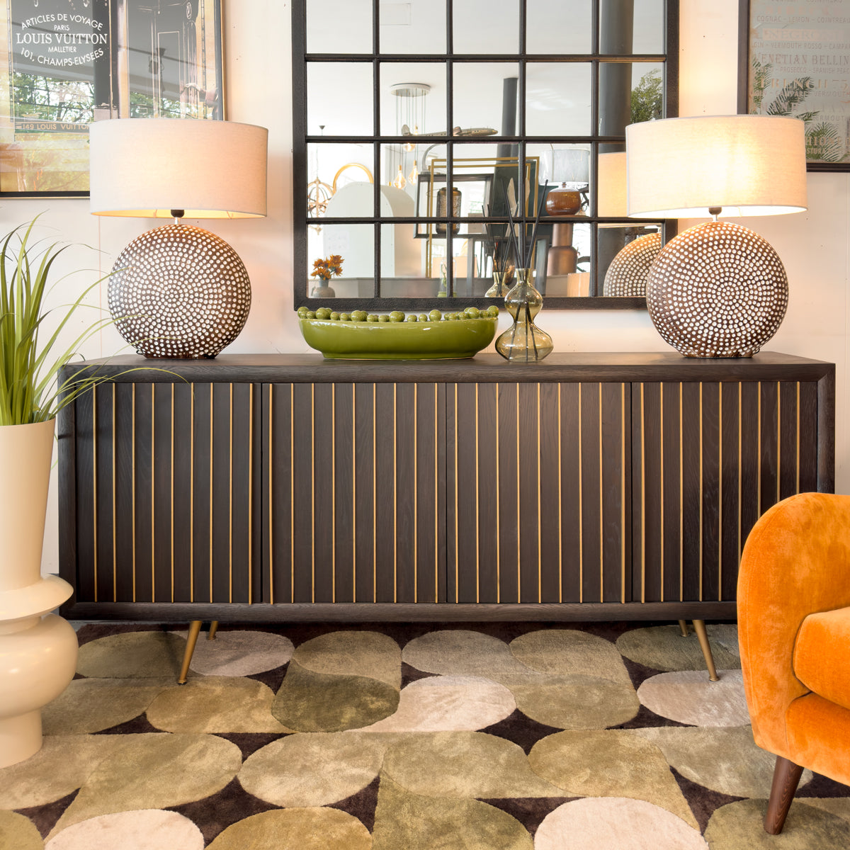 Decorative interior setting with a black striped sideboard, lamps, and a patterned rug.