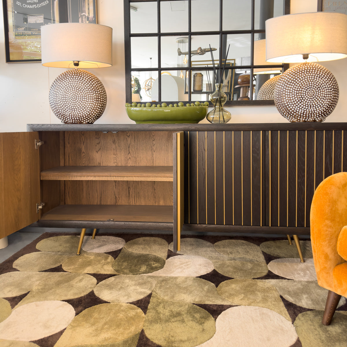 Modern interior with wooden slatted sideboard, decorative bowls, and a patterned rug.
