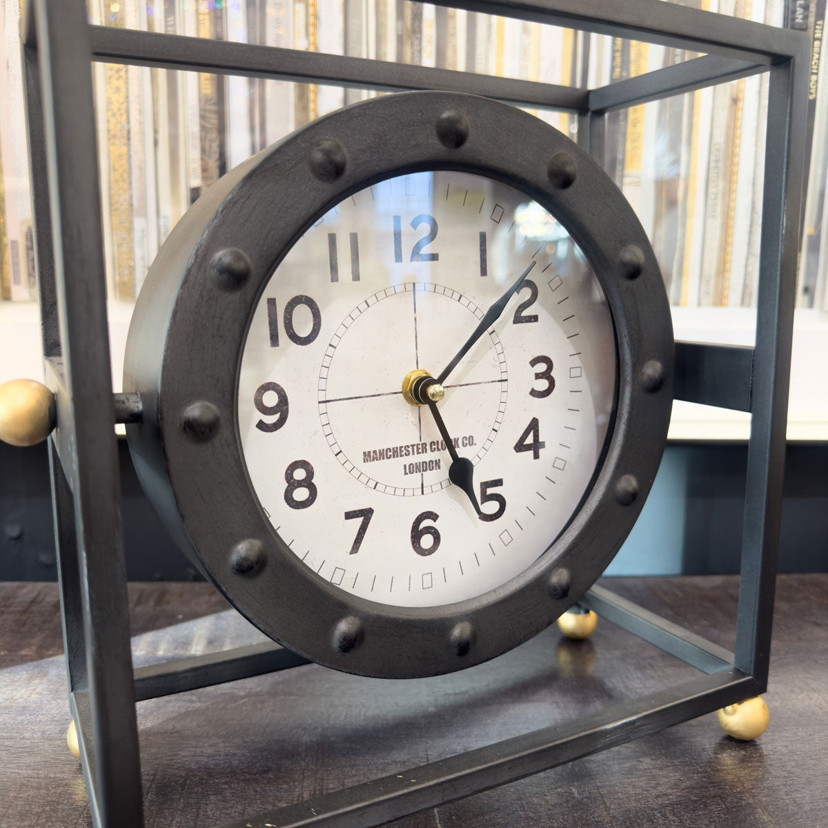 Decorative industrial clock with metallic frame on a wooden surface