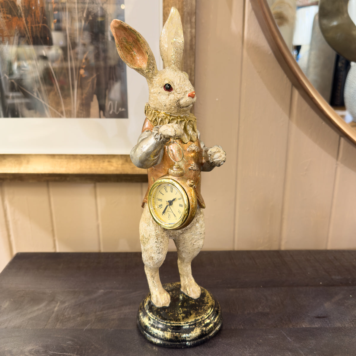 Decorative rabbit clock holding a small clock on a dark surface