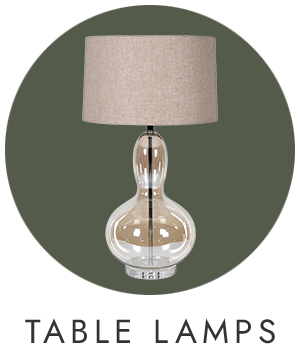 Table lamp with a clear glass base and beige fabric shade on a green background