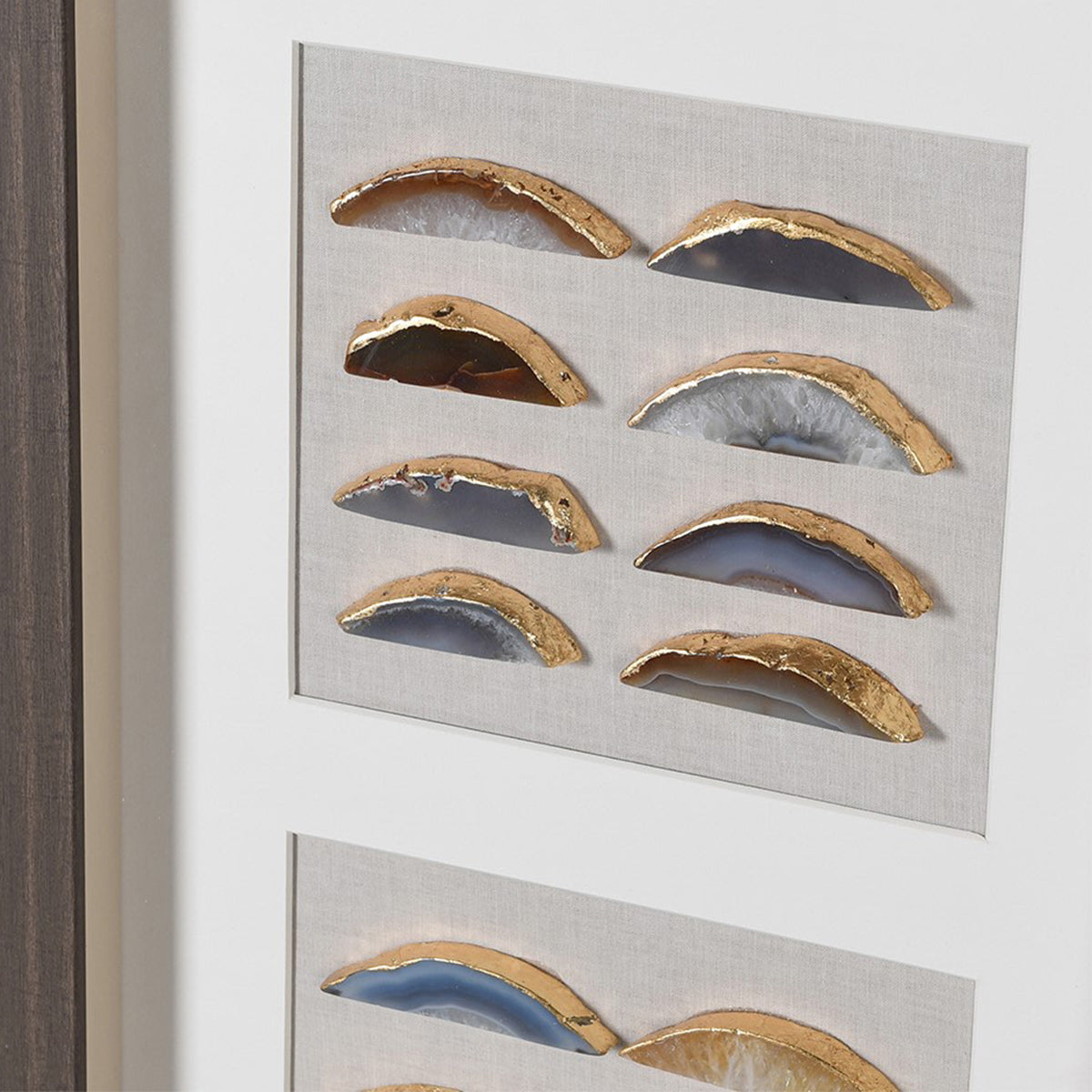 A close up of a framed wall art containing pieces of colourd agate stones, which have been finished with gold trims.