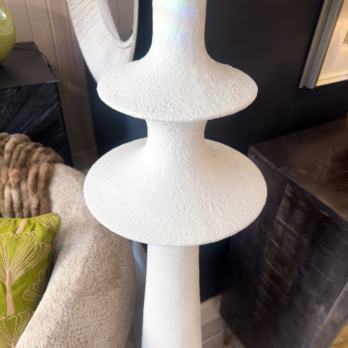 White textured lamp base next to a chair and sideboard