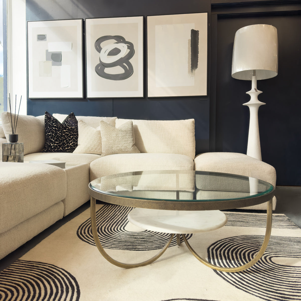 Modern living room with a beige sectional sofa, glass coffee table, and abstract art on the wall.