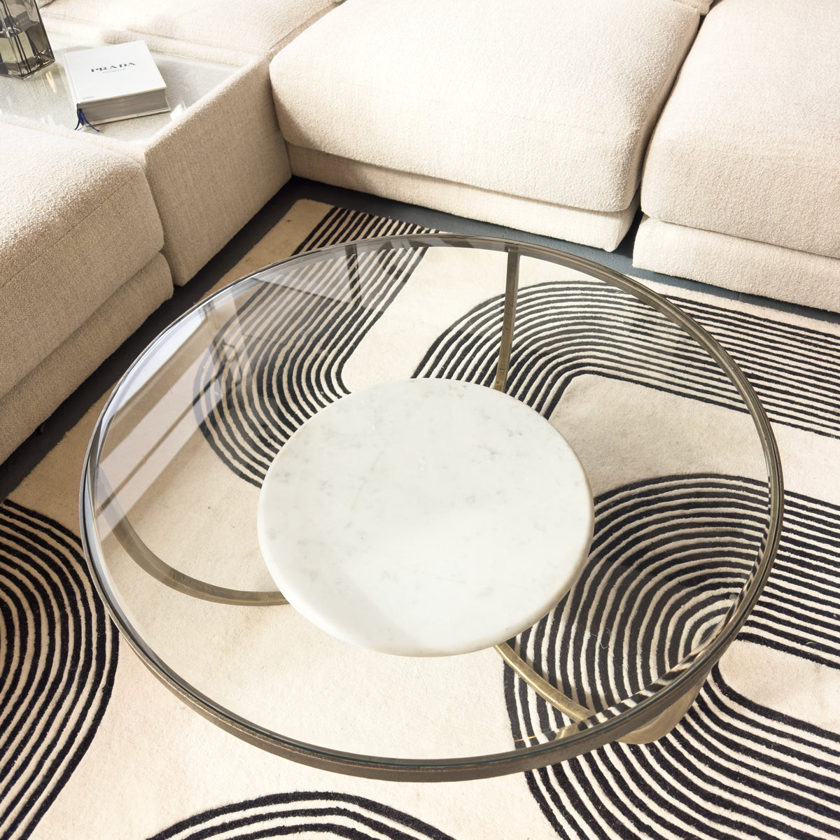 Modern glass coffee table with marble base in a living room setting