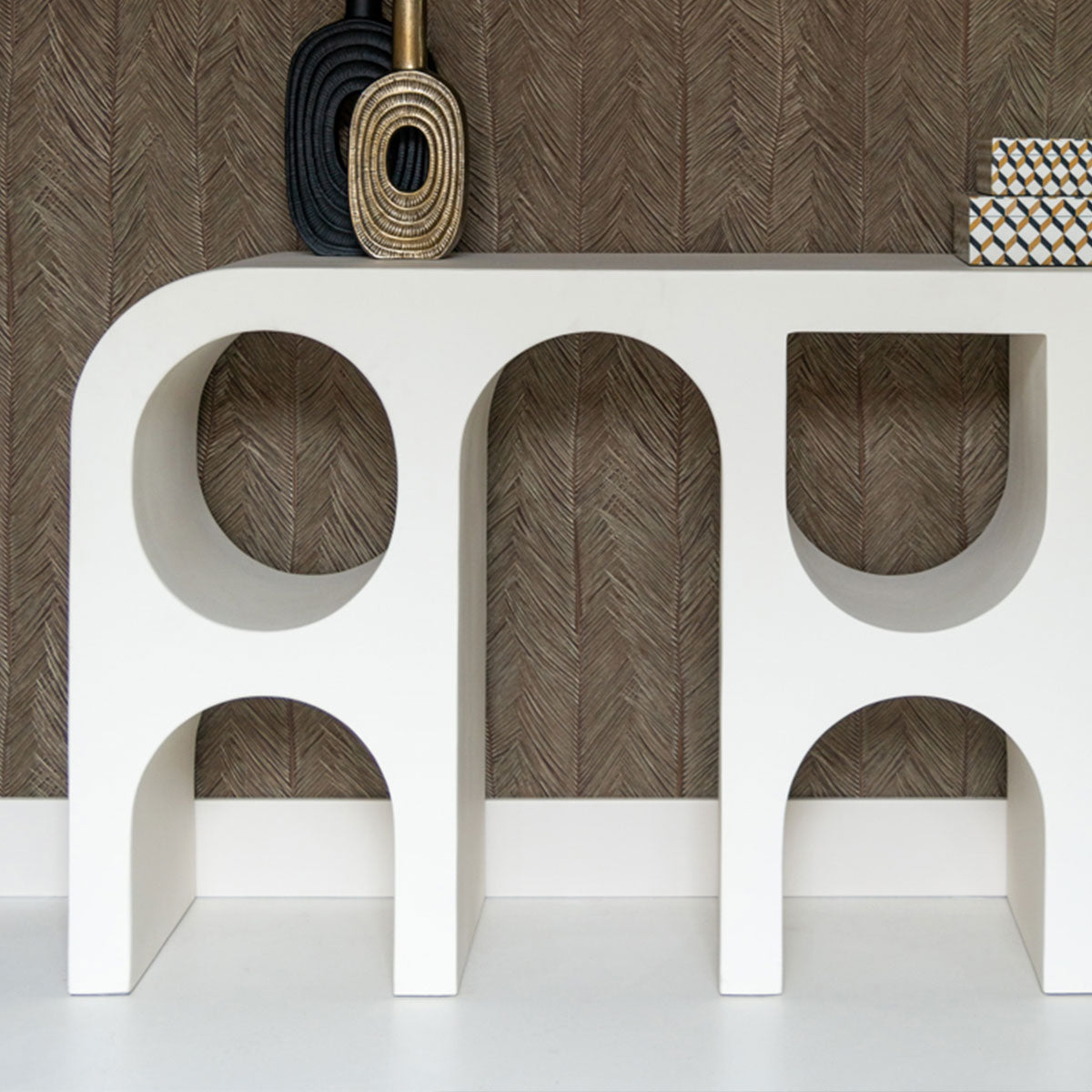 Modern console table with arched design against a wooden wall.