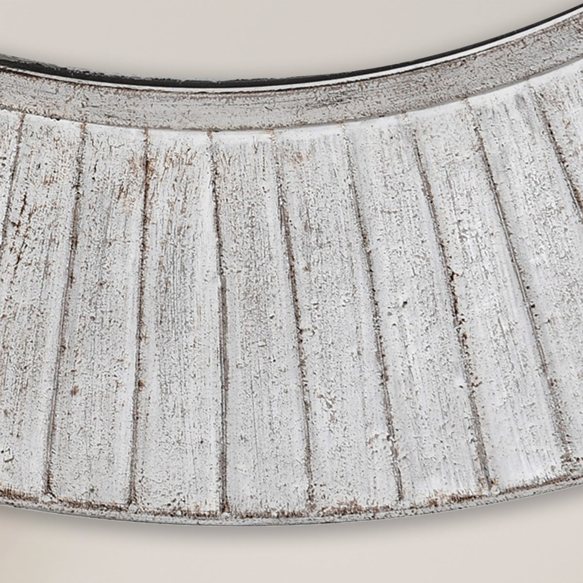 A close up of a distressed iron wall mirror with a white washed ridged frame.