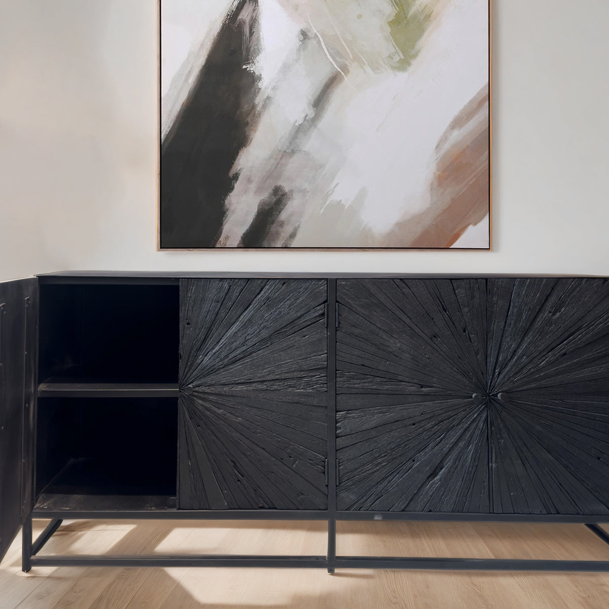 Black decorative cabinet with sunburst design doors in a room with abstract art on the wall.