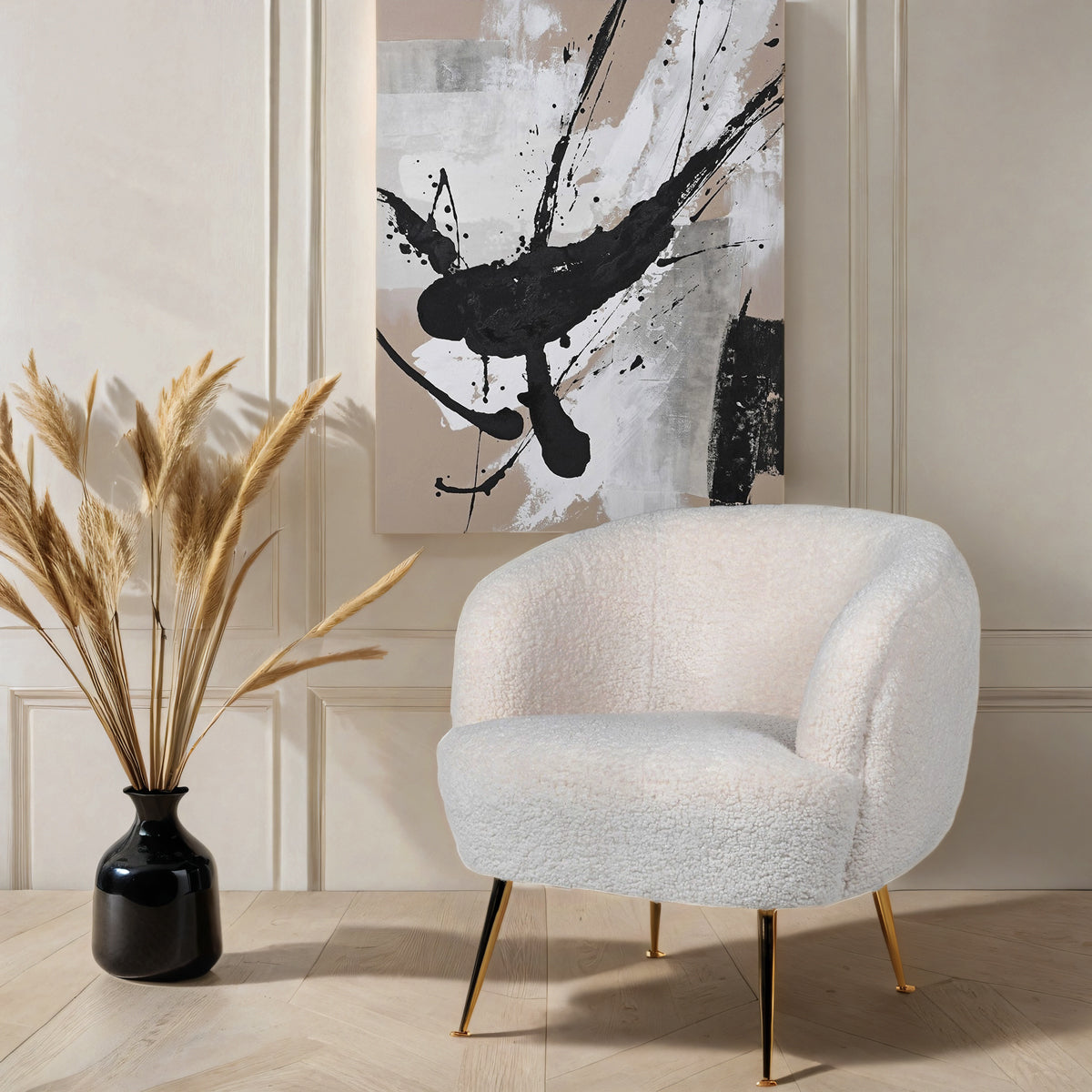 A white borg chair sitting next to a black vase with dried grass, below a beige abstract splatter canvas.