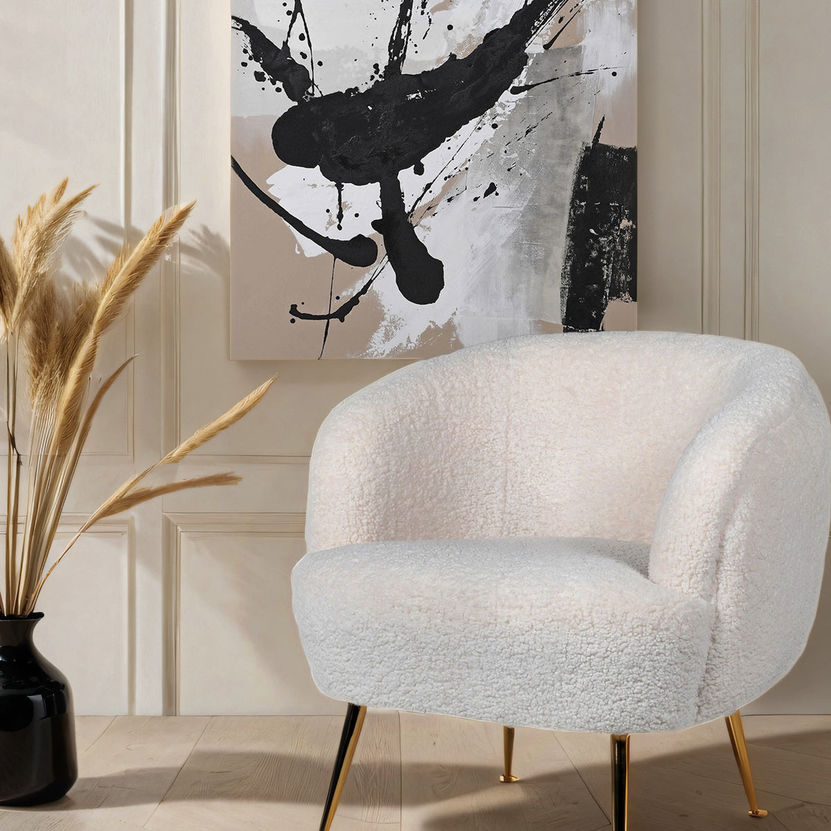 A white furry tub chair below an abstract art piece in tones of black, beige & white.