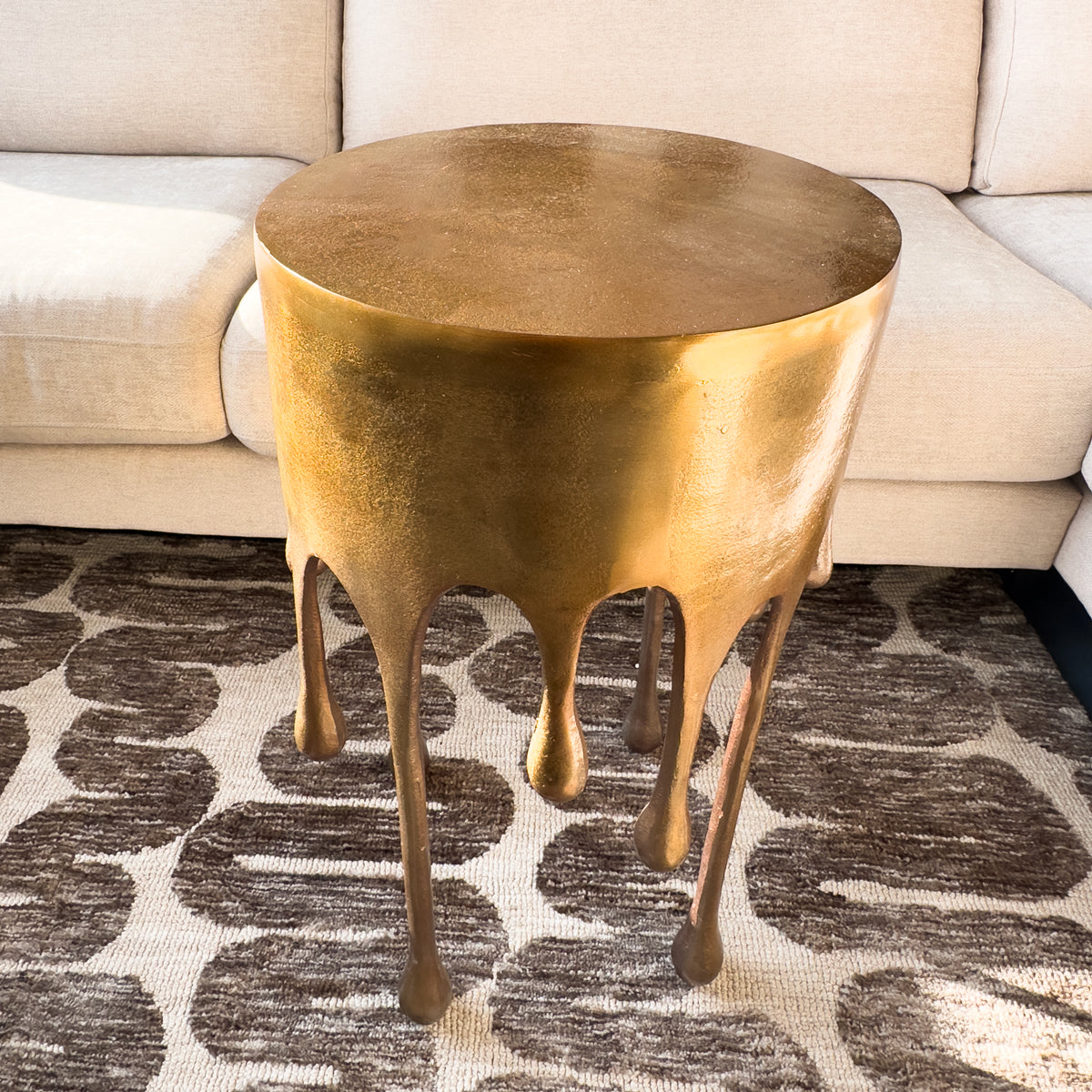 Gold side table with a unique design on a patterned rug
