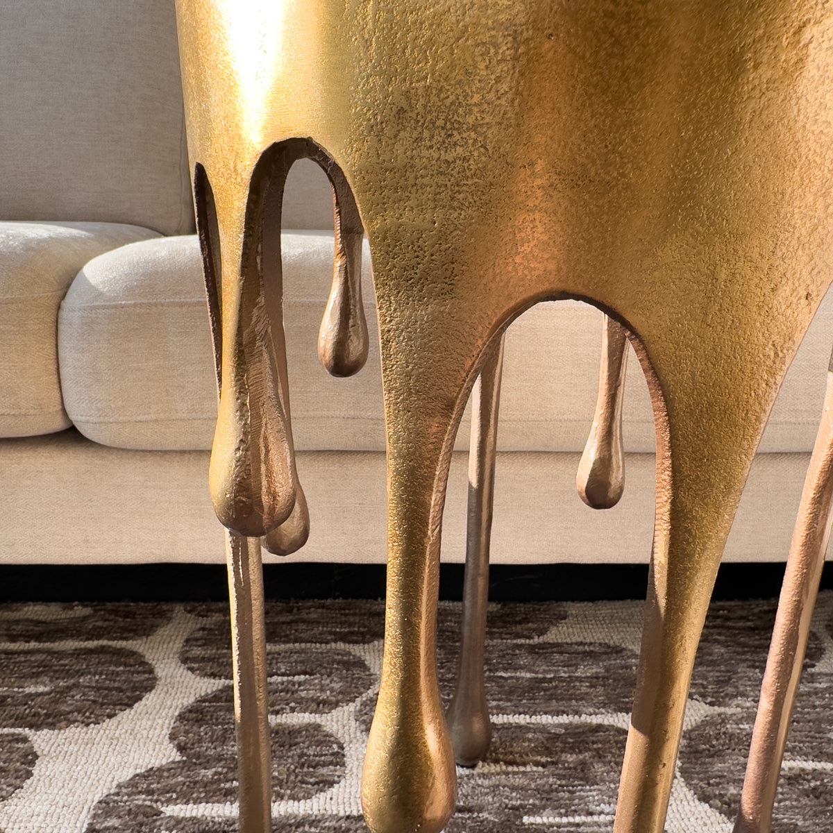 Gold metallic stool with a unique drip design in a living room setting