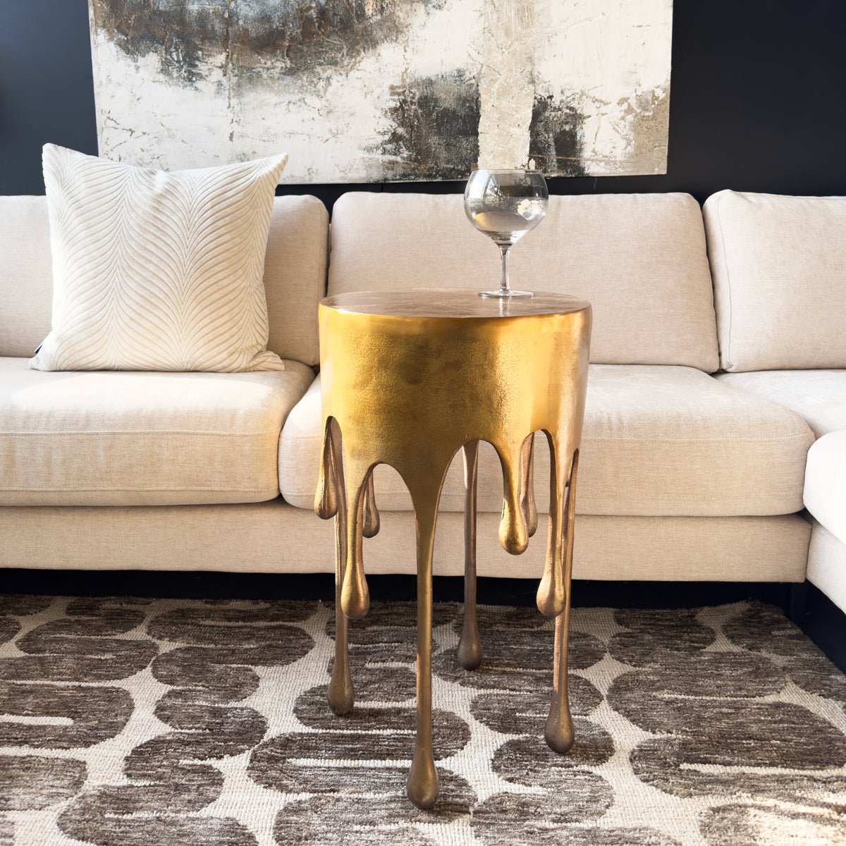Golden drip side table with a modern abstract painting in the background