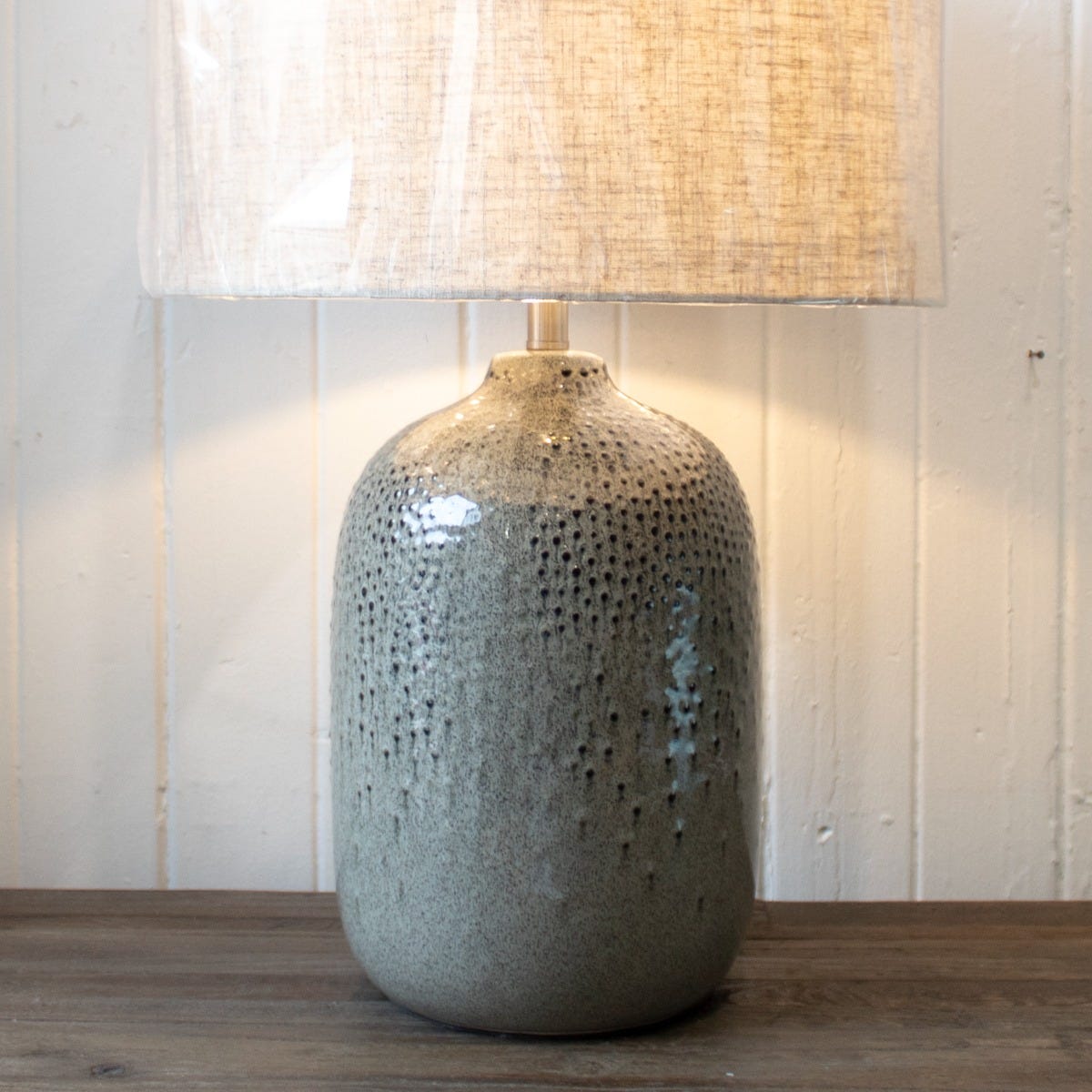 A green speckle texture table lamp with a neutral linen shade.