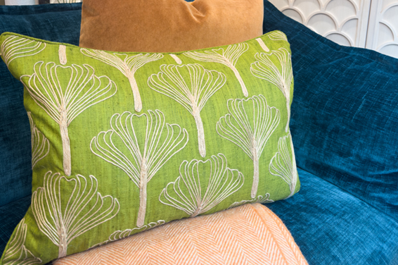 lime green gingko leaf embroidered cushion sitting on a blue sofa