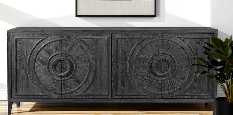 a black carved wood geometric sideboard on a oak floor with a plant in black pot